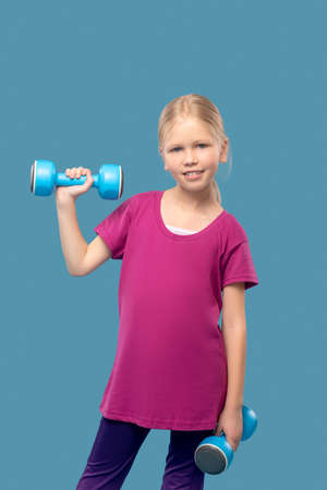 Girl in sportswear exercising with dumbbellsの写真素材