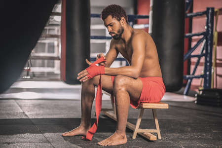 Dark-skinned athlete typing his hands with a red bandageの写真素材