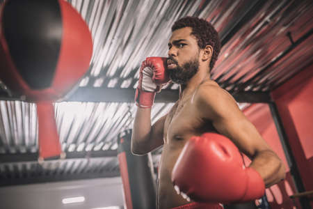 African american kickboxer having a workout in a gym and kicking the sandbagの写真素材