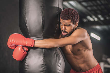 Young dark-skinned kickboxer having a workout in a gym and looking tiredの写真素材