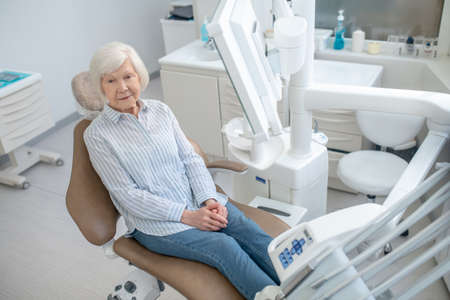 Gray-haired woman sitting at the dentists office and waiting for the doctorの写真素材