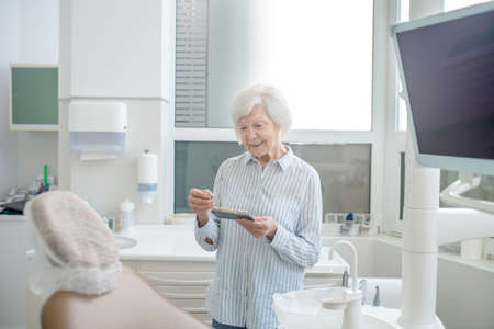 Senior woman at the dentists office with denture in handsの写真素材