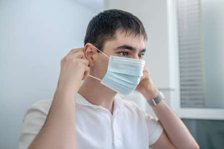 Young male doctor putting on a protective maskの写真素材