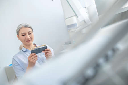Woman sitting at the dentists office and looking at the dental implantsの写真素材