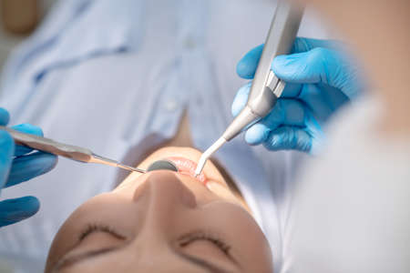 Dentist working on patients teeth restoration and making dental drillingの写真素材