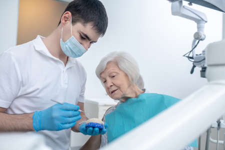 Male dentist talking to his senipr patient and explaining her diagnosisの写真素材