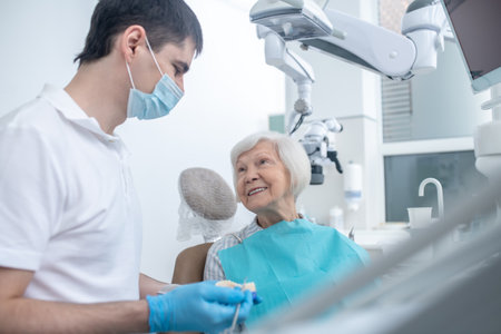 Male dentist talking to his senipr patient and explaining her diagnosis