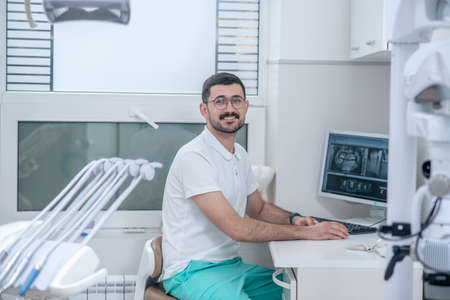 Young male dentist at his office looking busyの写真素材