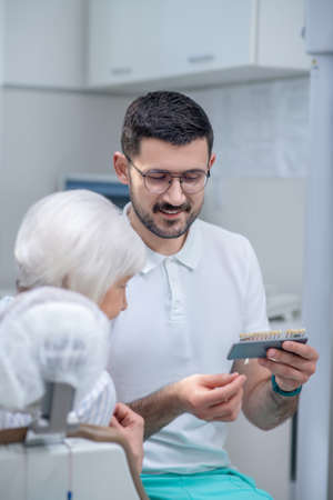 Male young dentist choosing dental implant with his patientの写真素材