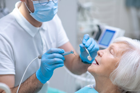 Dentist restoring teeth to the senior female patientの写真素材
