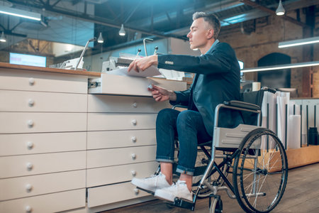 Man with papers sitting in wheelchair indoors