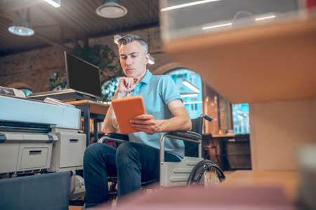 Serious man in wheelchair with tabletの写真素材