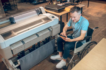 Smiling man in wheelchair looking at tabletの写真素材