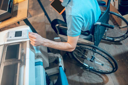 Hand of man on wheelchair near copy machineの写真素材