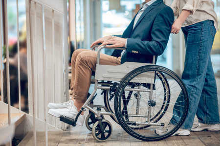 Man in wheelchair and accompanying assistantの写真素材