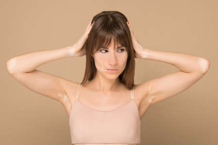 A long-haired young woman with skin pigmentation closing her earsの写真素材