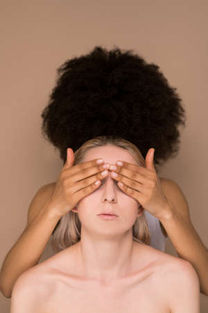 A dark-haired woman closing eyes to a blonde womanの写真素材