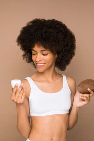 A young pretty curly-haired mulatta with a coconut and a jar of creamの写真素材