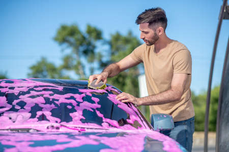 Profile of man wiping foam with napkin on carの写真素材