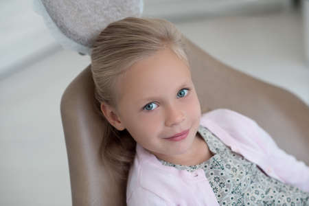 Cute blonde girl sitting in the chair at the dentistsの写真素材