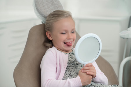 Cute blonde girl sitting in the chair at the dentistsの写真素材