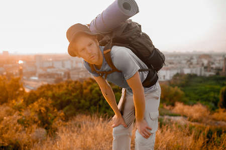 A male traveller with a backpack standing on the top of the hillの写真素材