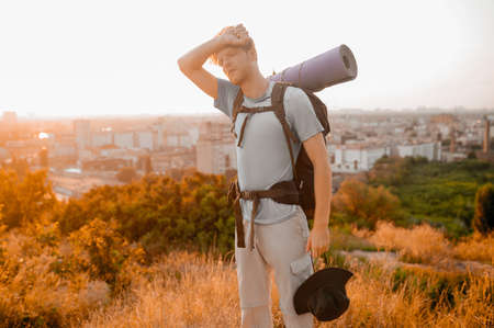 A tall man with a backpack feeling tired and exhausted