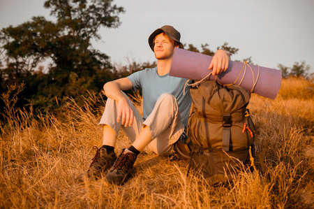 A male hiker sitting on the hill and relaxingの写真素材