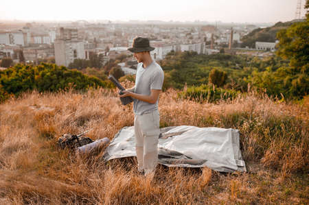 A man looking busy while putting the tent on the hill
