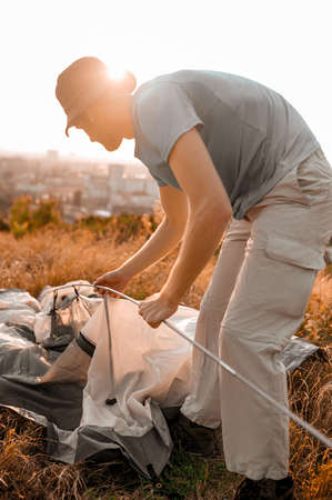 A young man pitching the tent on the hillの写真素材