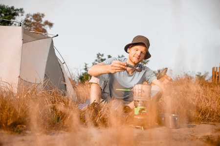 A male tourist having breakfast sitting near his tent