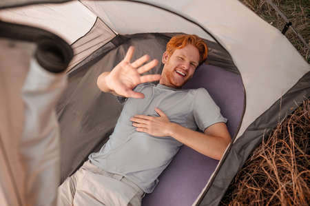 A ginger man looking joyful and stretching his handの写真素材