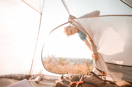 A man spening weekend in a countryside looking busy fixing the tentの写真素材