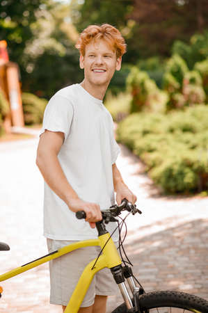 Contented male bike rider standing in a recreation parkの写真素材
