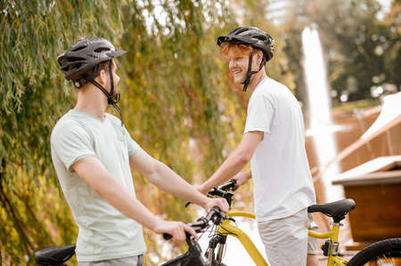 Two bike riders in protective headgear standing outdoorsの写真素材