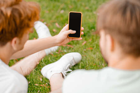 Two male friends using the smartphone outdoorsの写真素材