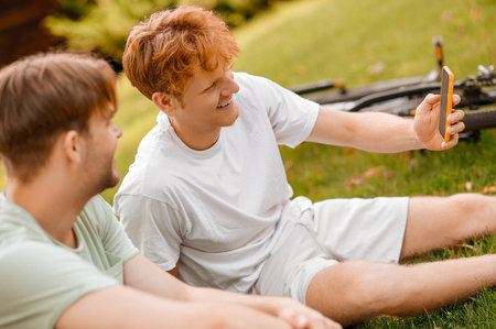Smiling guy showing something to his pal on his smartphoneの写真素材