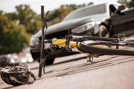 Bicycle and helmet lying on road and carの写真素材