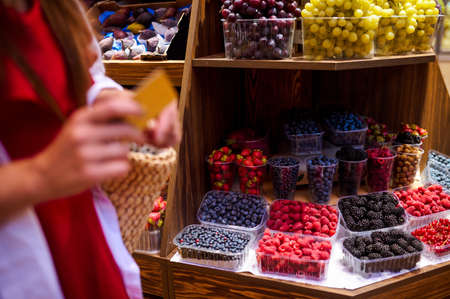 A woman holding a credit card in her hands while paying for fruits in a storeの写真素材