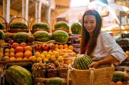 A young woman puting a watermelon into her bagの写真素材