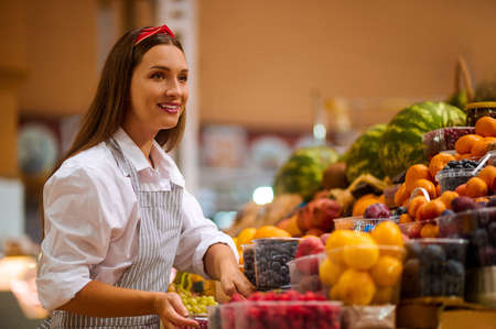 A pretty young woman in a fruits store choosing berriesの写真素材