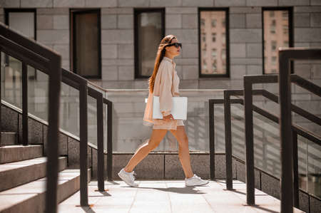 Fashionable young lady in beige in the city streetの写真素材