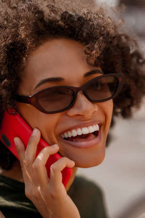 A close up picture of a smiling cute woman talking on the phoneの写真素材