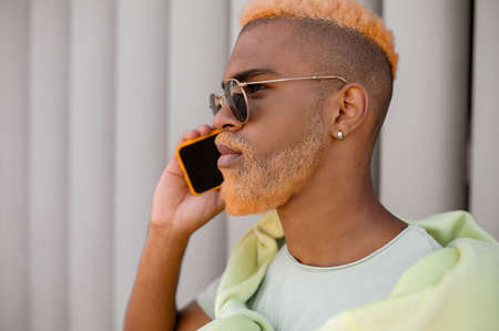 A waist up of a man with dyed hair talking on the phoneの写真素材