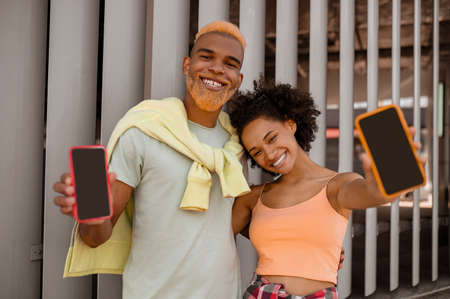A cute couple with smartphones in hands feeling good