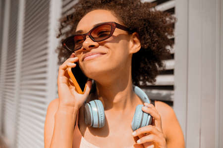 Curly-haired young woman talking on the phoneの写真素材