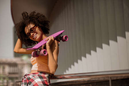 Cute young curly-haired woman with a skateboardの写真素材