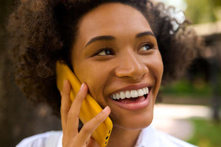 A curly-haired girl talking on the phone and looking pleasedの写真素材