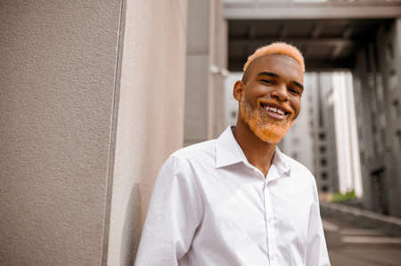 A picture of a tall dark-skinned man in white clothes on a urban backgroundの写真素材