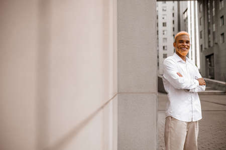 A picture of a tall dark-skinned man in white clothes on a urban backgroundの写真素材